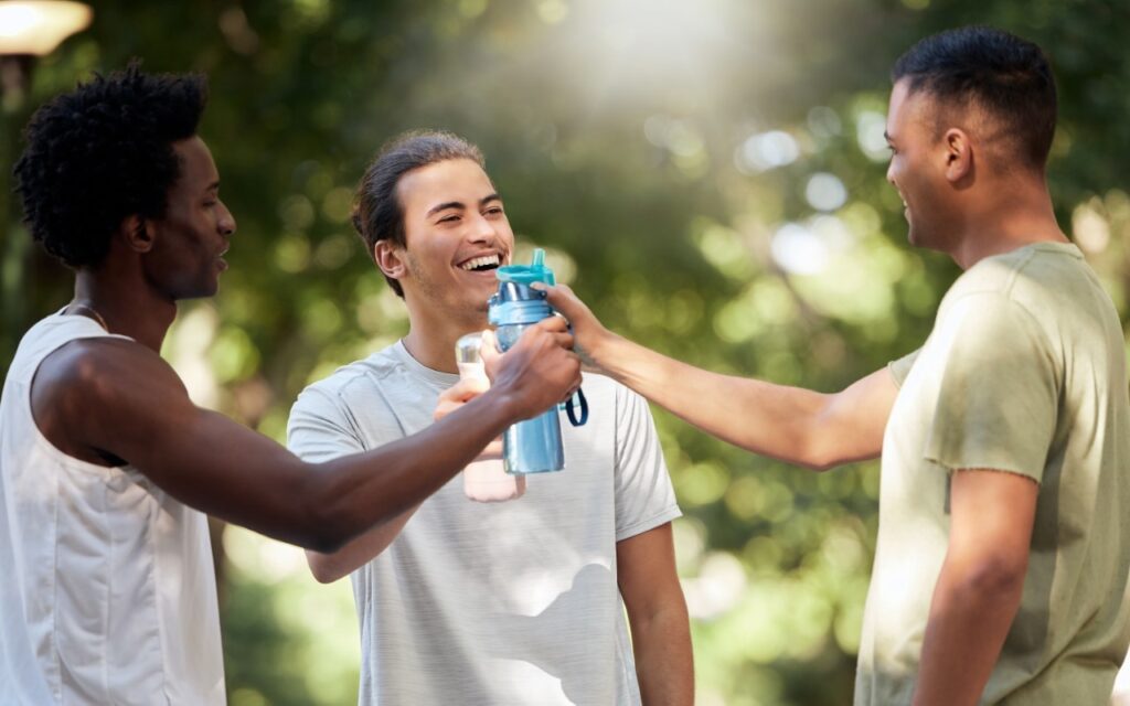 Three friends hydrating after outdoor exercise.