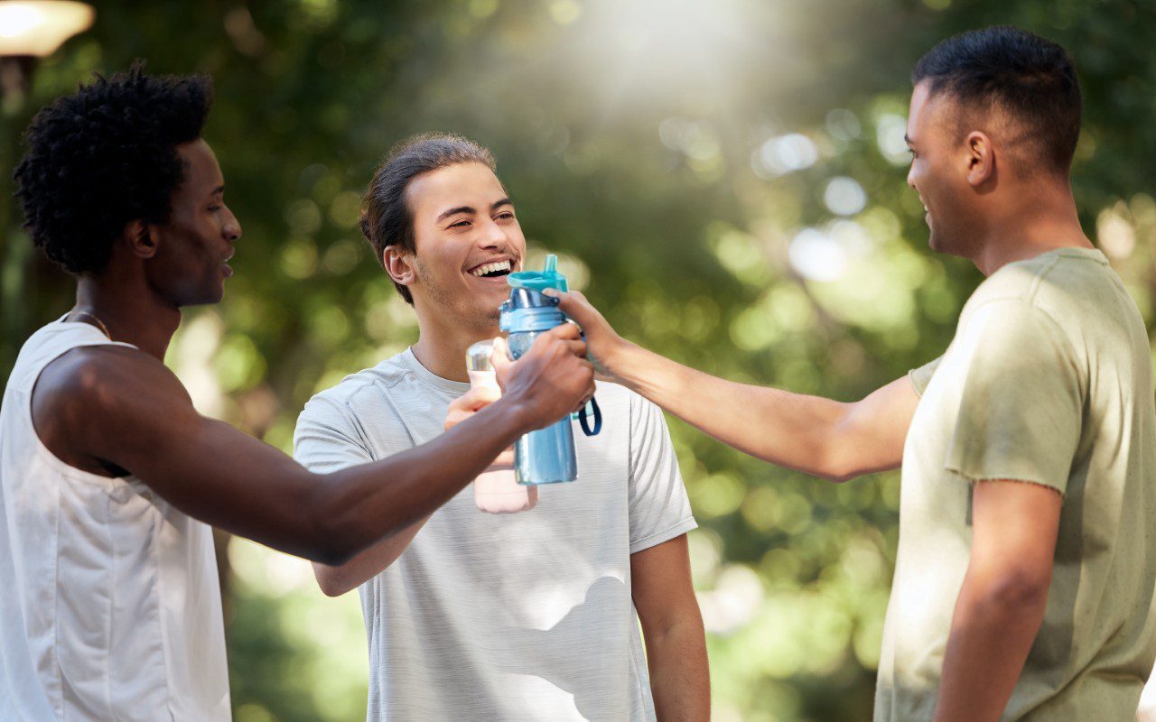 Three friends hydrating after outdoor exercise.